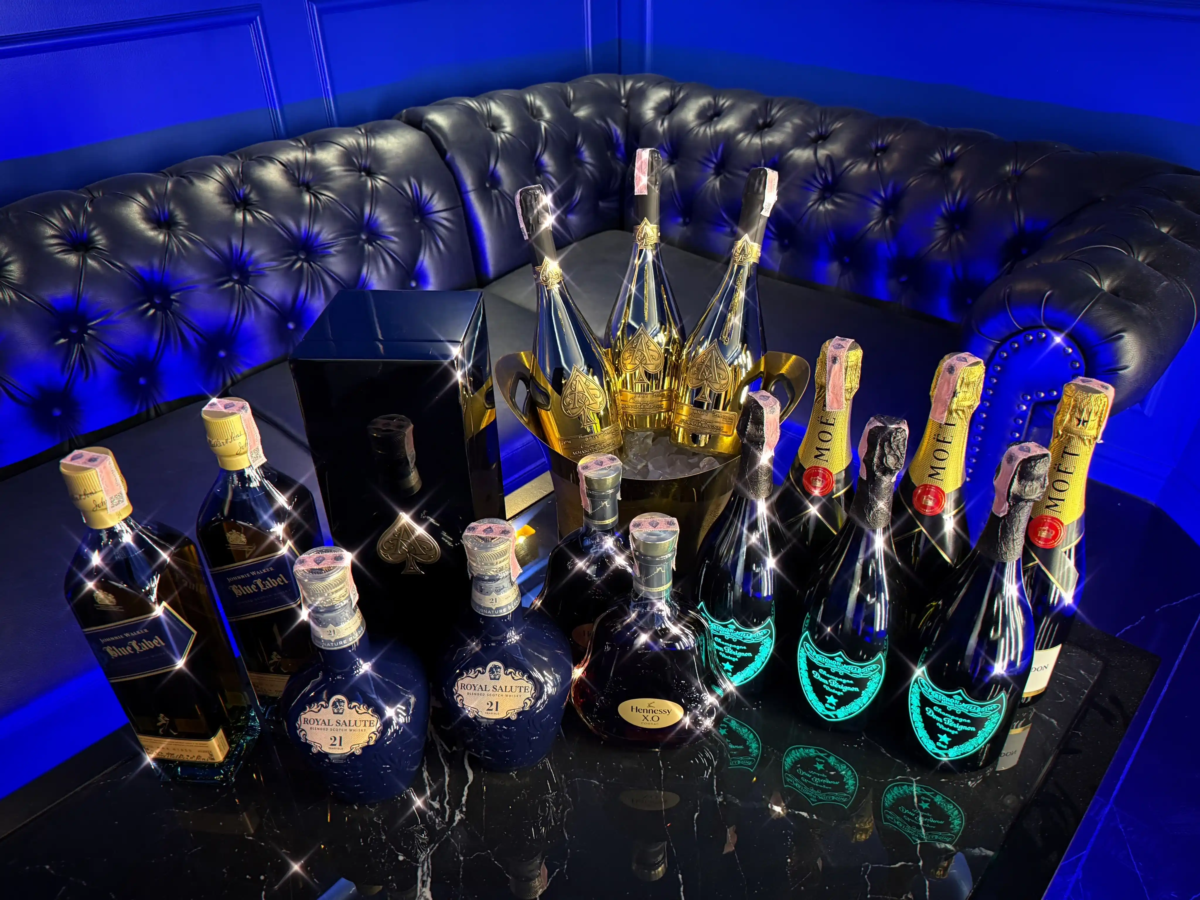 Premium bottles on a ZEUS table lit blue: Royal Salute, Dom Pérignon and Armand de Brignac