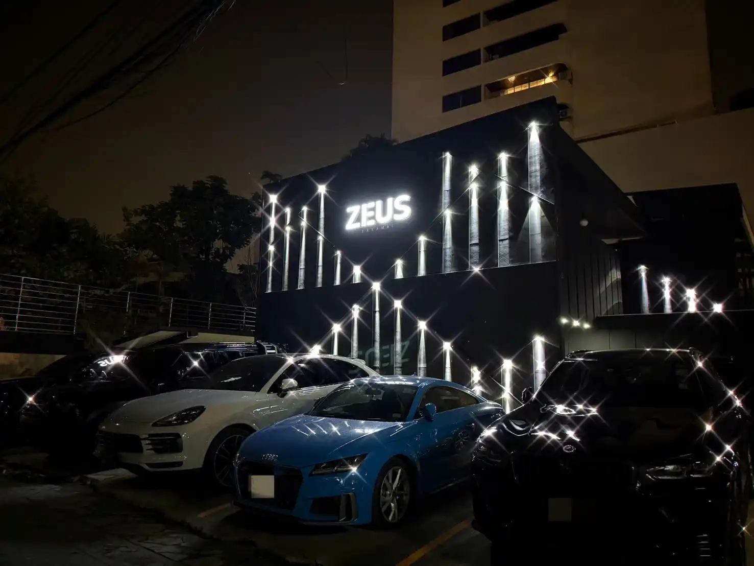 The ZEUS building at night on Ekkamai 12, with its light-bar facade and parked cars out front